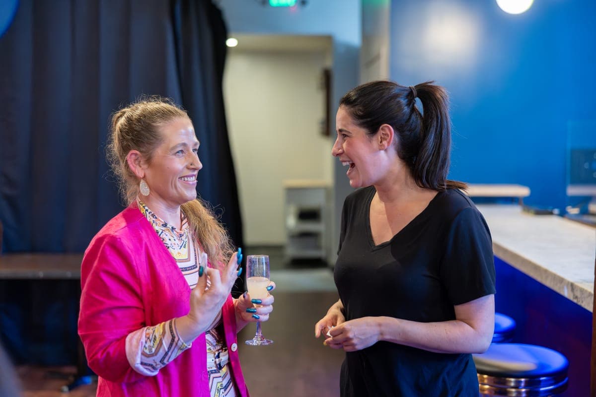 Two RealRoots members laughing together over drinks
